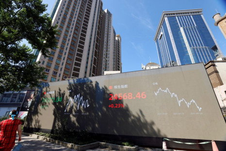 A woman walks by an electronic display showing the Shenzhen and Hang Seng stock indexes, in Shanghai, China, September 24, 2021. 