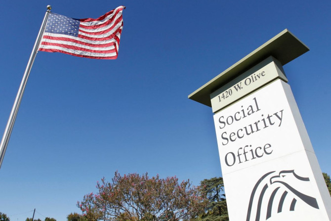 An American flag flutters in the wind next to signage for a United States Social Security Administration office in Burbank, California October 25, 2012. 