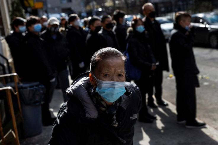 A woman wearing a protective face mask, amid the coronavirus disease (COVID-19) pandemic, walks during a funeral procession in the Chinatown section of the Manhattan borough of New York City, U.S., February 10, 2022.  
