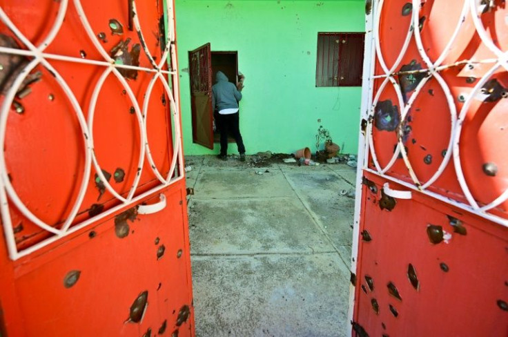 A man visits a ransacked house with bullet-riddled gates in Mexico's northern state of Zacatecas