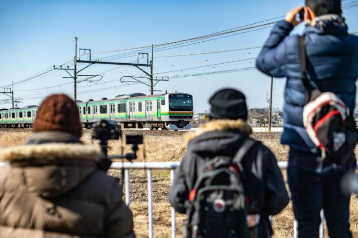 A group of Japan's "toritetsu" photograph a passing commuter train