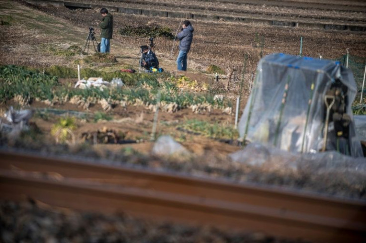 Japanese train photography enthusiasts set up along a railway track looking for the perfect shot