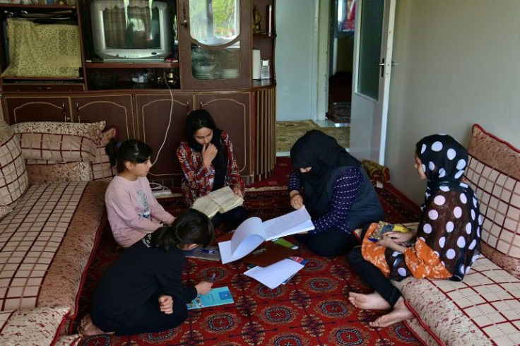 Girls study at home with their mother in Kabul after schools were closed Wednesday just hours after reopening