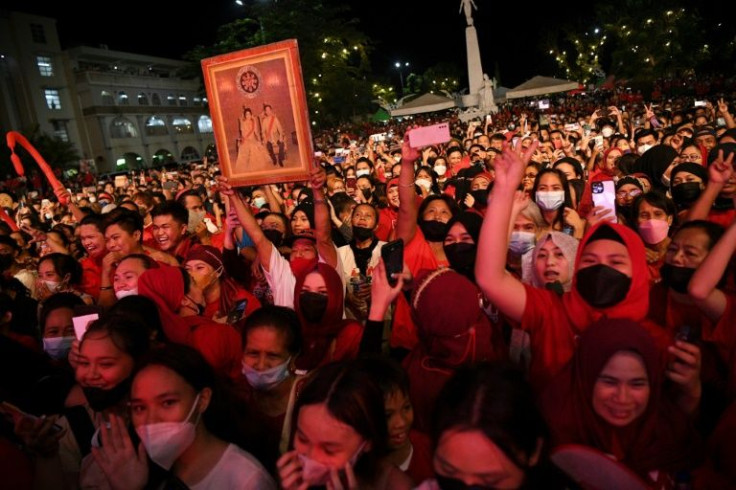 A supporter holds up a photo of the late dictator Ferdinand Marcos and former first lady Imelda Marcos during a rally for their grandson