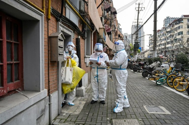 Health workers wearing protective gear work on a street in Jing'an district in Shanghai