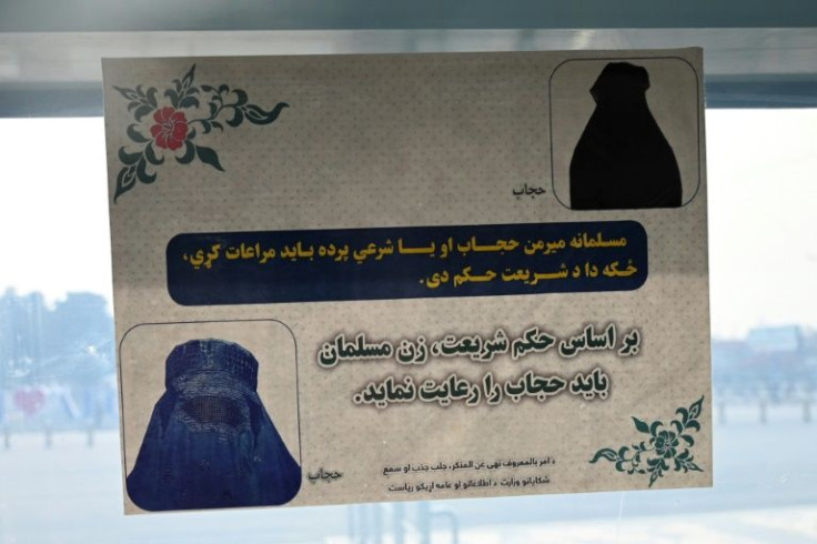 A poster ordering women to cover up is seen at a gate of Kabul's airport