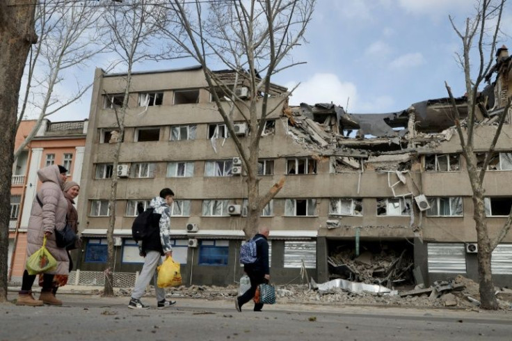 People walk past a damaged building in the Ukrainian city of Mykolaiv