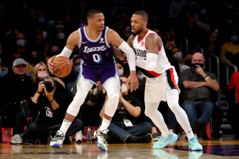 Russell Westbrook #0 of the Los Angeles Lakers handles the ball against Damian Lillard #0 and Larry Nance Jr. #11 of the Portland Trail Blazers 
