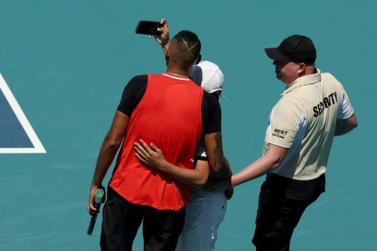 A spectator runs on court and takes a selfie with Nick Kyrgios during the Australian's tempestuous loss to Jannik Sinner at the Miami Open