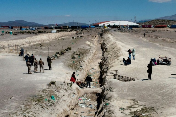 Migrants cross the the border trench near Pisiga from Bolivia into Chile