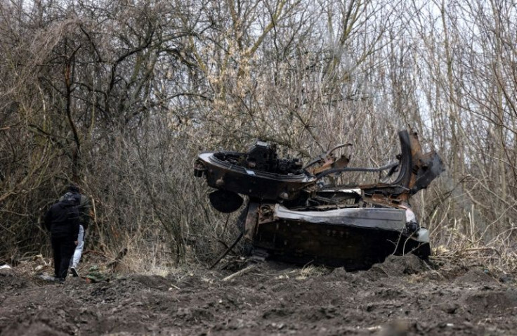 Residents walk past a destroyed Russian tank in the village of Lukianivka near Kyiv on Wednesday