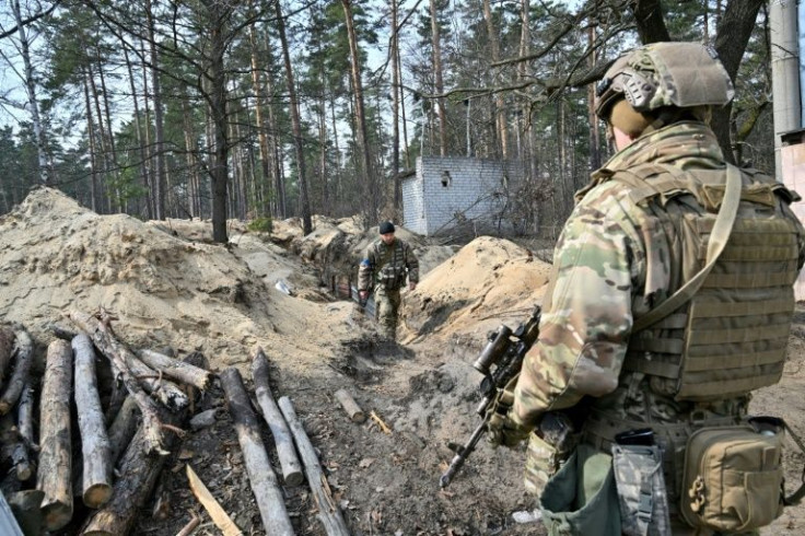Ukrainian servicemen survey the area from their position along the front line, north of the Ukrainian capital of Kyiv on March 31, 2022