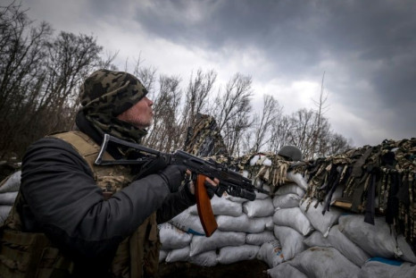 A Ukrainian serviceman holds an assault rifle in a trench at the front line east of Kharkiv on March 31, 2022