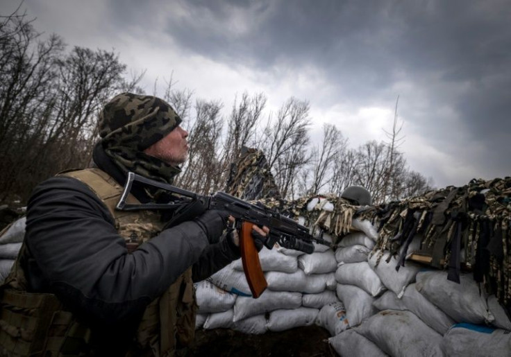 A Ukrainian serviceman holds an assault rifle in a trench at the front line east of Kharkiv on March 31, 2022
