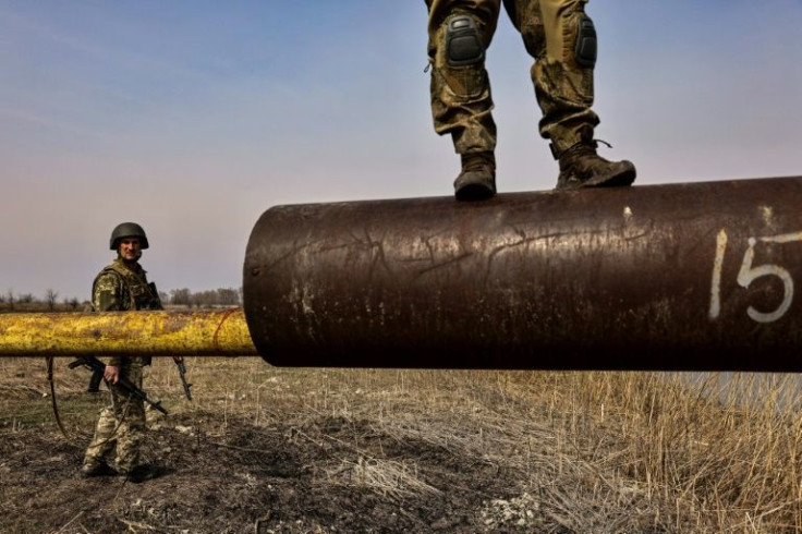 A Ukranian soldier stands on the cannon of a burnt Russian tank on the outskirts of Kyiv, on March 31, 2022
