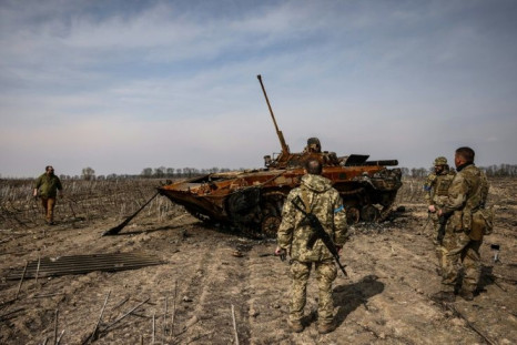 Ukrainian soldiers stand by a burnt Russian tank on the outskirts of Kyiv, on March 31, 2022