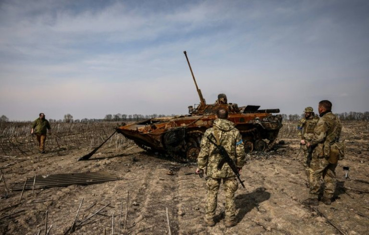 Ukrainian soldiers stand by a burnt Russian tank on the outskirts of Kyiv, on March 31, 2022