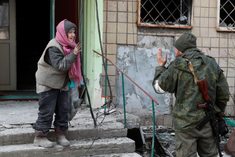 A local resident speaks to a service member of pro-Russian troops outside an apartment building damaged during Ukraine-Russia conflict in the besieged southern port city of Mariupol, Ukraine March 31, 2022. 