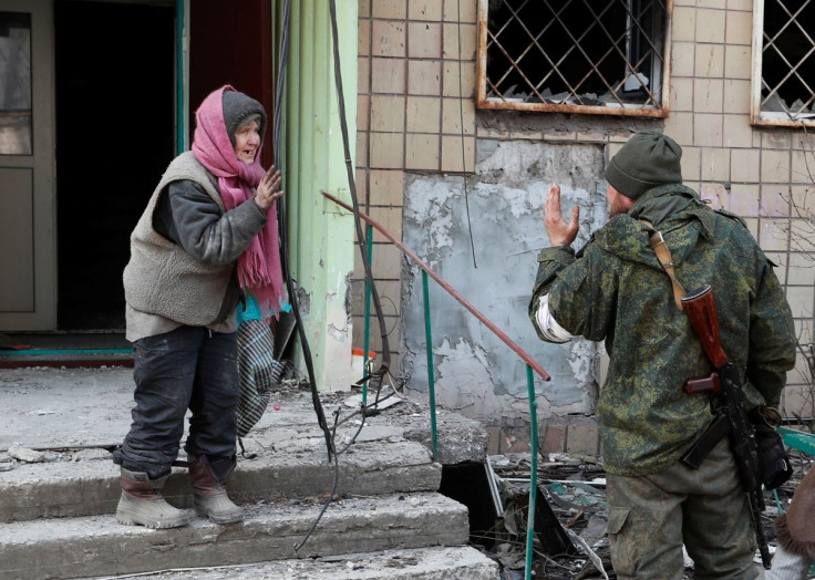 A local resident speaks to a service member of pro-Russian troops outside an apartment building damaged during Ukraine-Russia conflict in the besieged southern port city of Mariupol, Ukraine March 31, 2022. 