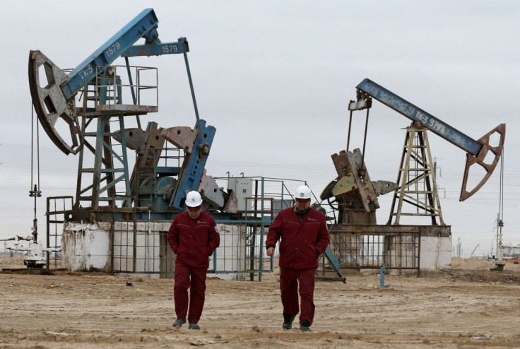 Workers walk as oil pumps are seen in the background in the Uzen oil and gas field in the Mangistau Region of Kazakhstan November 13, 2021. 