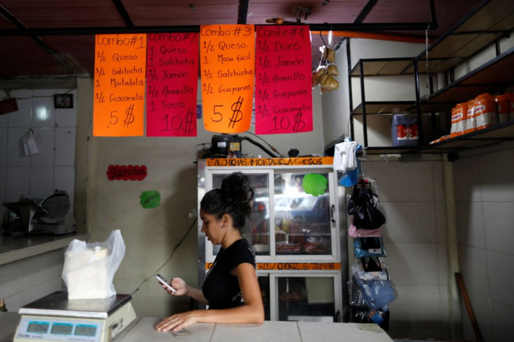 A worker checks her phone in a store that sells sausages in a market in Caracas, Venezuela, August 12, 2021. 