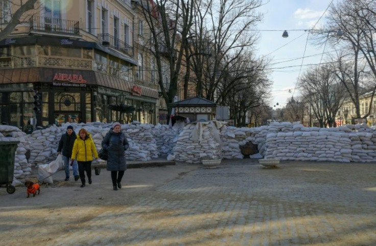 People walk in downtown Odessa, which has been transformed by sandbags and metal tank barriers
