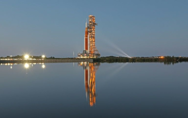 The massive Artemis I rocket is illuminated at dusk atop a mobile launch platform en route to Launch Pad 39B from the Vehicle Assembly Building at the Kennedy Space Center in Florida