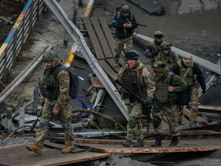 Ukrainian servicemen walk on a destroyed bridge as Russia's invasion of Ukraine continues, in the town of Irpin outside Kyiv, Ukraine April 1, 2022.