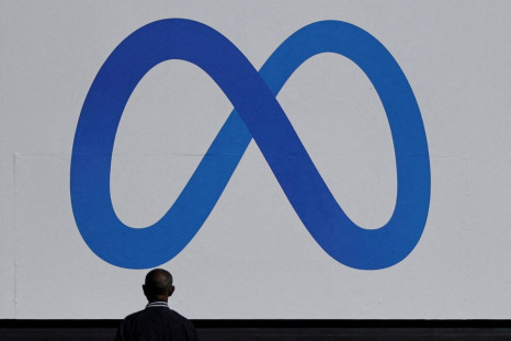 A man stands in front of a sign of Meta, the new name for the company formerly known as Facebook, at its headquarters in Menlo Park, California, U.S. October 28, 2021. 