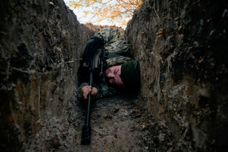 A Ukrainian soldier hides from a helicopter airstrike amid Russia's invasion of Ukraine, near Demydiv, Ukraine March 10, 2022.  