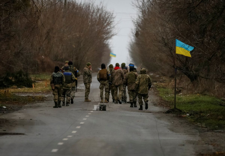 Ukrainian service members walk near a Ukrainian flag, amid Russia's invasion of Ukraine, in the village of Kozarovychi, in Kyiv region, Ukraine April 2, 2022.