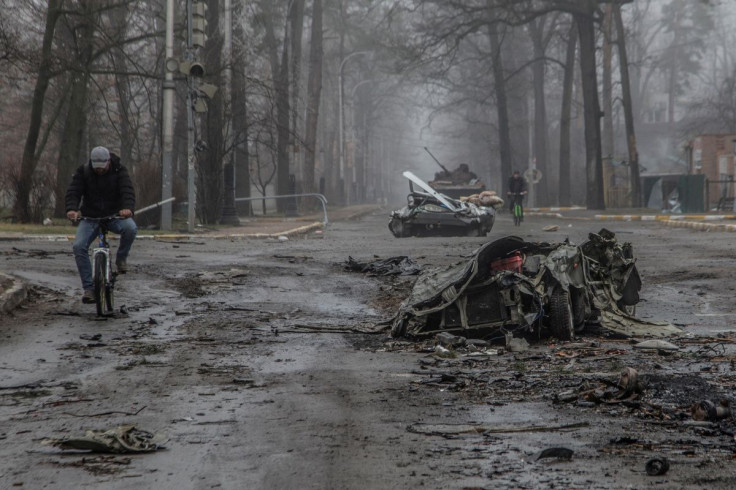 Local residents ride bicycles past flattened civilian cars, as Russia's attack on Ukraine continues, on a street in the town of Bucha, in Kyiv region, Ukraine April 1, 2022.