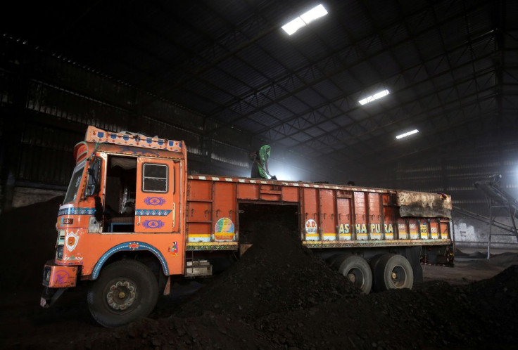 A worker shovels coal in a supply truck at a yard on the outskirts of Ahmedabad, India, October 25, 2018. 