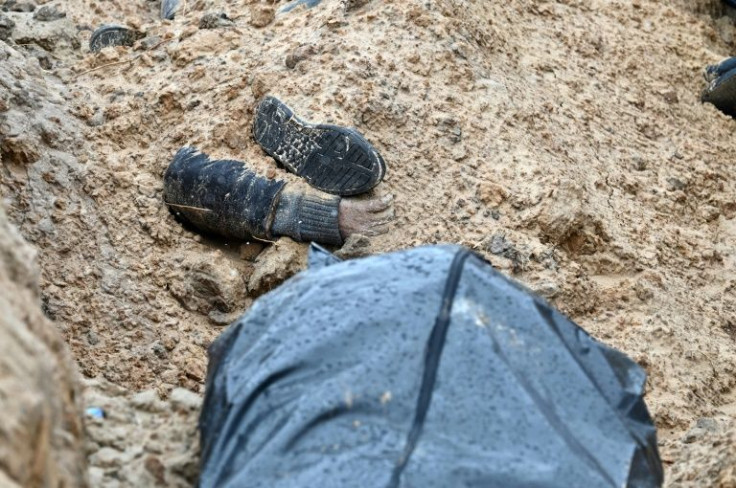 A partially buried body is seen in a mass grave in the town of Bucha