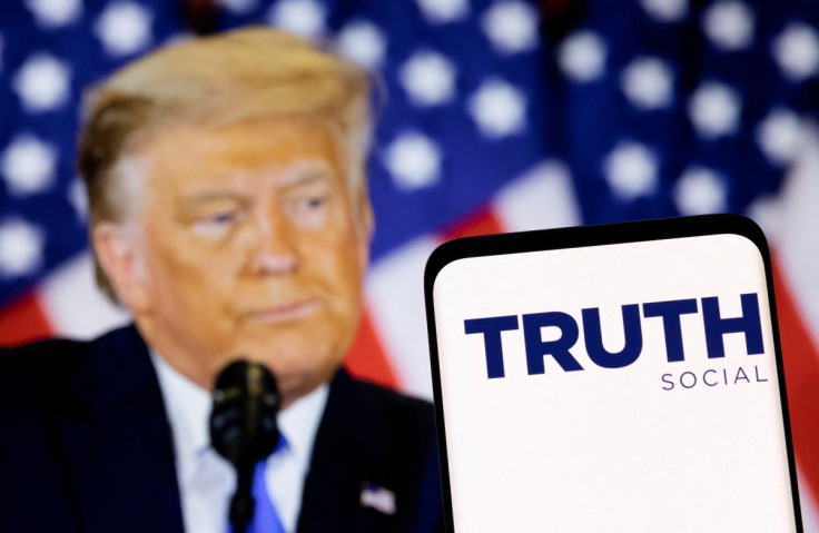 The Truth social network logo is seen on a smartphone in front of a display of former U.S. President Donald Trump in this picture illustration taken February 21, 2022. 