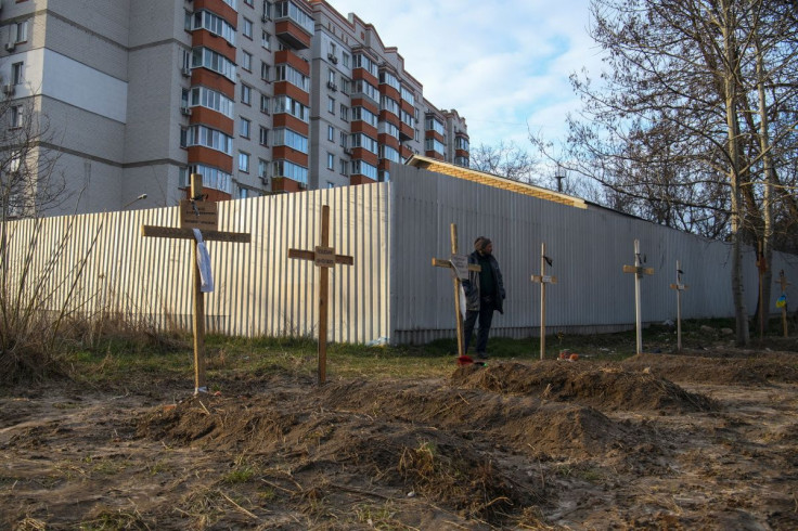 A man stands next to graves with bodies of civilians, who according to local residents were killed by Russian soldiers, as Russia's attack on Ukraine continues, in Bucha, in Kyiv region, Ukraine April 4, 2022.