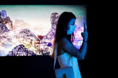 A visitor takes a photo in front of a video installation "Glows in the Night" by Chinese contemporary artist Yang Yongliang, which will be converted into NFTs and auctioned online at Sotheby's, at the Digital Art Fair, in Hong Kong, China September 30, 20