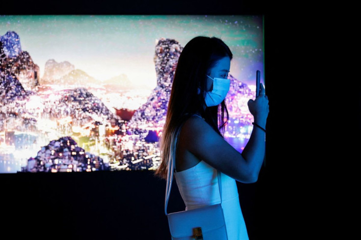 A visitor takes a photo in front of a video installation "Glows in the Night" by Chinese contemporary artist Yang Yongliang, which will be converted into NFTs and auctioned online at Sotheby's, at the Digital Art Fair, in Hong Kong, China September 30, 20