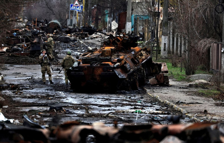 A soldier takes a photograph of his comrade as he poses beside a destroyed Russian tank and armoured vehicles, amid Russia's invasion on Ukraine in Bucha, in Kyiv region, Ukraine April 2, 2022. 