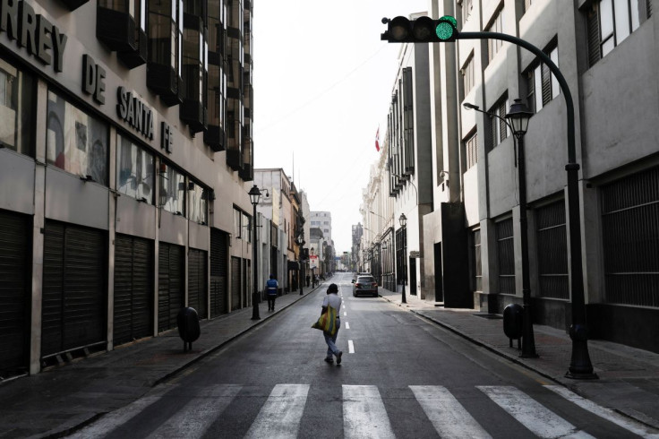 A person walks in the middle of a mostly empty street after Peru's President Pedro Castillo imposed a curfew in the capital Lima, banning people from leaving their homes in an attempt to curb protests against rising fuel and fertilizer costs that have spr