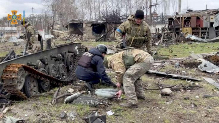 State Emergency Service members collect ordnance after Russia's withdrawal from the area, in Bucha, Ukraine, in this still image taken from video uploaded to a social media website on April 4, 2022. State Emergency Service in Kyiv Oblast/Handout via REUTE