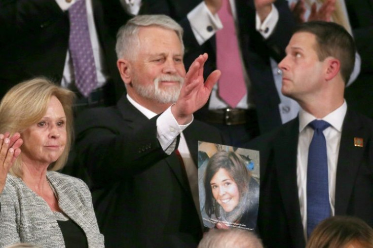 Carl Mueller (C) holds a photo of his daughter, Kayla, as his wife Marsha (L) looks on during the 2020 State of the Union address