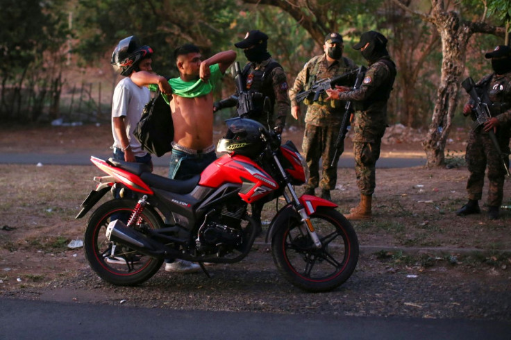 A soldier checks a man's tattoos at a checkpoint in the Distrito Italia neighbourhood after El Salvador's Congress approved emergency powers that temporarily suspended some constitutional protections after the Central American country recorded a sharp ris