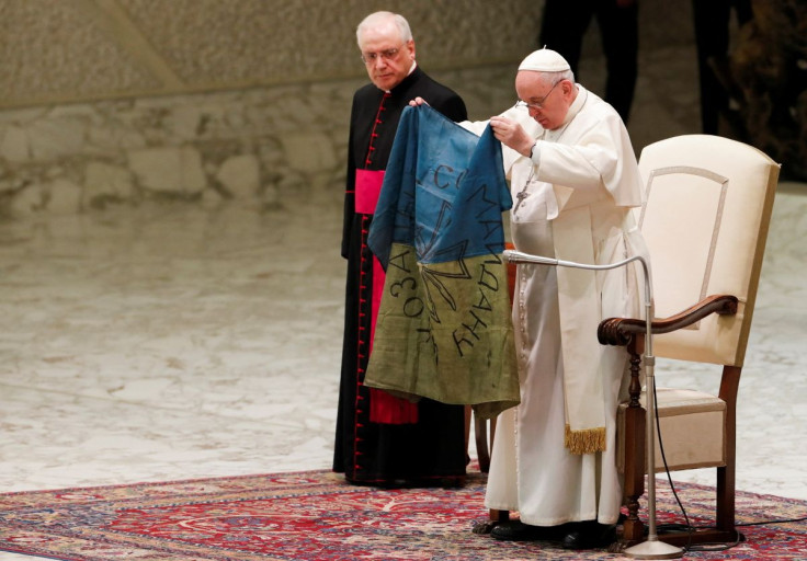 Pope Francis holds the Ukrainian flag that was sent to him from the town of Bucha where tied bodies were shot at close range, a mass grave and other signs of executions were found, during the weekly general audience at the Paul VI Hall at the Vatican, Apr