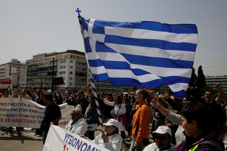 A woman holds a Greek flag as she takes part in a protest during a 24-hour strike over high prices and low wages in Athens, Greece, April 6, 2022.