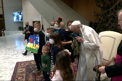 Pope Francis kisses the Ukrainian flag that was sent to him from the town of Bucha where tied civilians were shot at close range, a mass grave and other signs of executions were found, during the weekly general audience at the Paul VI Hall at the Vatican,