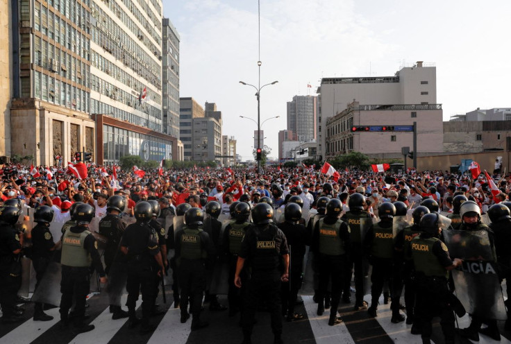 Riot police stand next to demonstrators during a protest against Peru's President Pedro Castillo after he had issued a curfew mandate, which was lifted following widespread defiance on the streets, as protests spiralled against rising fuel and fertilizer 