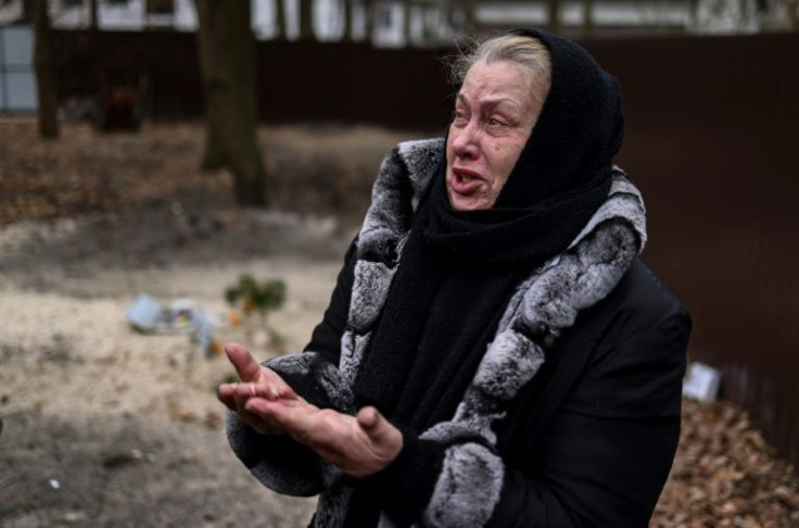 Tetiana Ustymenko weeps over the grave of her son and his two friends