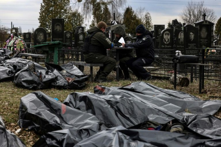 Some bodies are stacked on top of each other, others lie side by side on the ground in crumpled black body bags