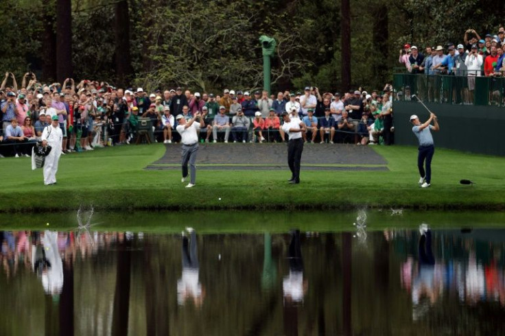 Fred Couples, Tiger Woods and Justin Thomas skip balls skip balls across the lake on the 16th hole during a practice round prior to the 86th Masters at Augusta National Golf Club
